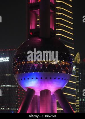 Blick auf den hell erleuchteten Oriental Pearl Tower bei Nacht, mit leuchtenden Rosa- und Blautönen, die einen Schimmer gegen den dunklen Himmel werfen, Shanghai, Shangha Stockfoto