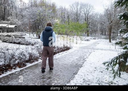 Hübscher junger kaukasischer Mann, der im Winter im verschneiten Park davonläuft. Outdoor Lifestyle Stockfoto