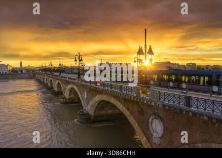 Der Blick aus der Vogelperspektive auf die Brücke Pont de Pierre leuchtet mit der untergehenden Sonne über dem Fluss Garonne, die einen warmen Farbton auf das Wasser wirft, Bordeaux, Nouvelle-Aquita Stockfoto