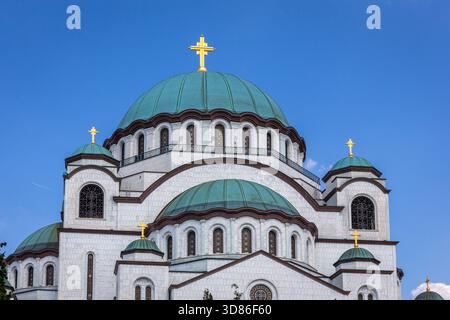 Die Kirche St. Sava, serbisch-orthodoxe Kirche in Belgrad, Serbien, mit weißer Marmorfassade, großer grüner Kuppel und vergoldetem Kreuz, blauem Himmel. Stockfoto
