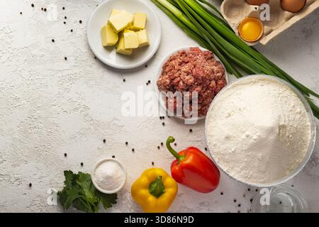 Frische Zutaten werden auf einer Arbeitsplatte angeordnet, darunter Hackfleisch, bunte Paprika, Butter, Zwiebeln, Eier, Mehl Stockfoto