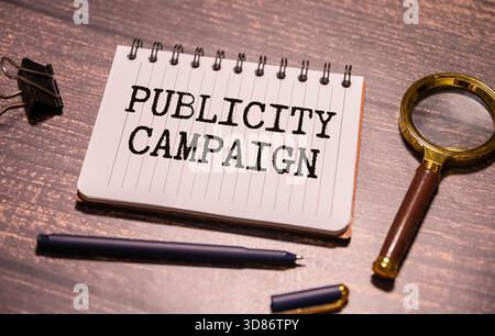 Die Worte Werbekosten werden in schwarzen Buchstaben auf gelbem Notizpapier geschrieben. Ein gelber Stift ist im Hintergrund des blauen Tagebuchs eingebettet. Stockfoto