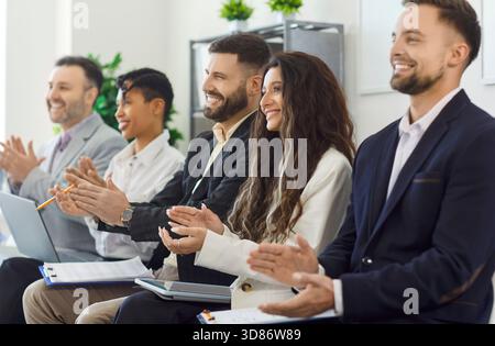 Gruppe von Geschäftsleuten, die dem Redner applaudieren und zuhören, die an einer öffentlichen Konferenz teilnehmen Stockfoto