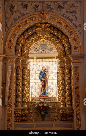 Statue des heiligen Josephs mit Jesus Christus auf seinem Schoß, sichtbar auf dem Altar der christlichen Kirche des heiligen Sebastian von Pedreira in Lissabon Stockfoto