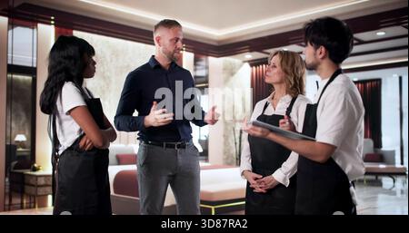 Der Hotelmanager leitet Ein Team-Meeting im Raum. Stockfoto