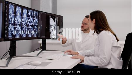 Männlicher Chirurg, der MRT-Röntgenaufnahmen auf Desktop-Computermonitoren analysiert Stockfoto
