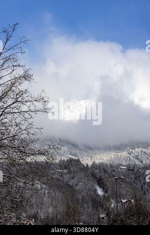 Wunderschöner Blick auf die Schneebirge der Alpen über der Stadt, Wolken vor dem blauen Himmel, Innsbruck, Österreich Stockfoto