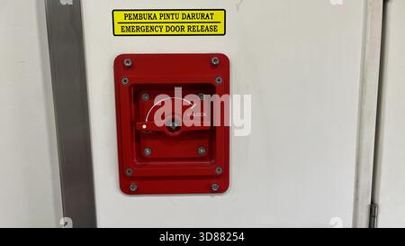 Eine rote Notentriegelungstaste mit gelbem Aufkleber Stockfoto