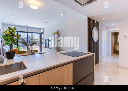 Schicke Marmor-Kücheninsel mit Blick auf den Flur, stilvoller Einrichtung und hellem Wohnbereich in Torrevieja. Stockfoto