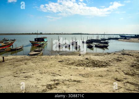 Farbenfrohe Boote an einem ruhigen Ufer des Flusses unter einem hellen blauen Himmel vor Anker Stockfoto