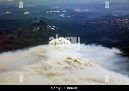Aus der Vogelperspektive erhebt sich Rauchwolken aus dem Lanin-Nationalpark in Patagonien, Argentinien, und dem Lanin-Vulkan auf der anderen Seite der Grenze in der Ferne. Stockfoto
