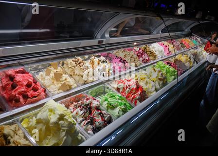 Eine Vitrine mit verschiedenen Eissorten zum Verkauf und Kunden auf den Straßen von Budva am Abend. Montenegro Stockfoto