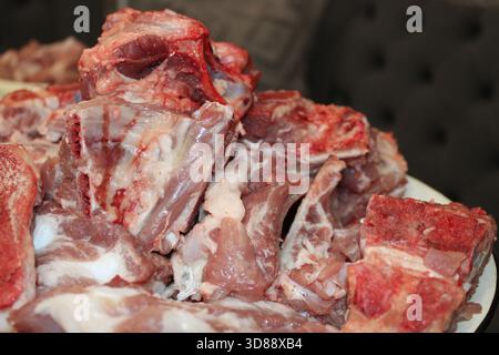 Verschiedene Stücke von frischem rohem Fleisch werden auf einer Platte zum Kochen angeordnet. Die Umgebung schlägt vor, dass die Küche voll auf eine Mahlzeit vorbereitet wird. Stockfoto