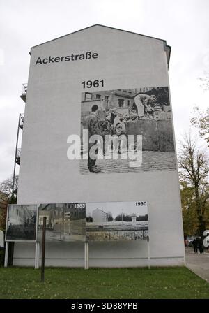 Berliner Mauer, Deutschland. Der Bau begann am 13. August 1961 und fiel am 9. November 1989. Die Regierung der Deutschen Demokratischen Republik (DDR) baute diese über 150 km lange Barriere, um Ost-Berlin vollständig von der übrigen DDR zu isolieren. Gedenkstätte Berliner Mauer in der Bernauer Straße. Gebäude an der Ecke Ackerstraße. Tafeln mit historischen Fotografien, die den Bau und die Abschnitte der Mauer zeigen. Nach dem Mauerbau sperrte die DDR-Polizei die bestehenden Türen zur Bernauer Straße ein. Die Fenster der Häuser wurden nach mehreren Berlinern sukzessive gemauert Stockfoto