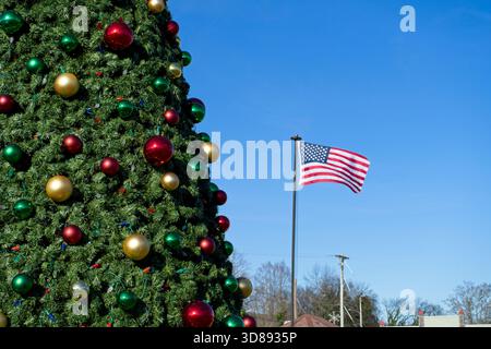Großer Weihnachtsbaum mit Ornamenten und amerikanischer Flagge im blauen Himmel Stockfoto