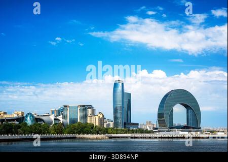 Blick auf die moderne Skyline von Baku entlang des kaspischen Ufers mit Glastürmen und zeitgenössischer Architektur unter blauem Himmel. Stockfoto