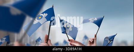 CIs-Fahnen in den Händen auf einem verschwommenen urbanen Hintergrund. Die Fotoillustration wurde ohne künstliche Intelligenz erstellt, nur mit Photoshop. Stockfoto