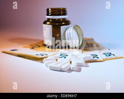 Arzneimittelkosten: Pillen & Euro - Pillen aus einer Arzneimittelflasche mit 50-Euro-Banknoten, symbolisiert die hohen Kosten für Medikamente und Gesundheitsdienstleistungen Stockfoto