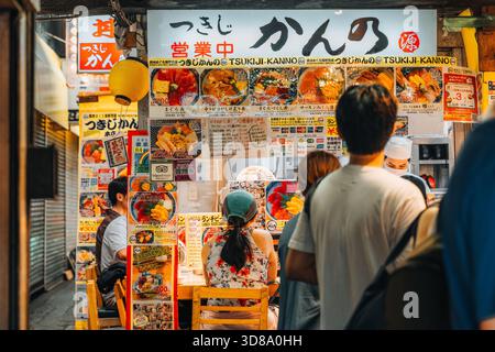 Gäste stehen in einem belebten Tsukiji Kanno Fischrestaurant an, das auf frische Reisschüsseln wartet. Stockfoto