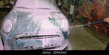 Berlin, Deutschland - 18. Mai 2025: Mini Cooper wird mit Schaum in einer bunten Autowaschanlage gewaschen. Stockfoto