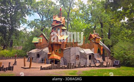 Berlin, Deutschland - 08. September 2025: Farbenfrohe Holzspielplatz-Struktur umgeben von Bäumen in einer lebhaften grünen Parklandschaft. Stockfoto