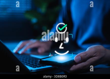 Gesichtserkennung und biometrisches Authentifizierungskonzept für Gesichtserkennung. Benutzer mit Smartphone, Gesichts-Scan-Symbol und Häkchen, die für Cybersicherheit stehen, Stockfoto