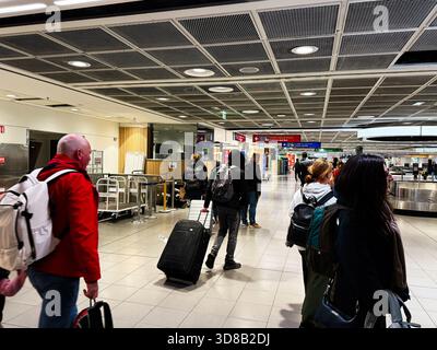 Dublin, Irland - 21. Oktober 2025: Passagiere mit Rucksäcken und Koffern bewegen sich über ein geräumiges Flughafenterminal in Dublin. Stockfoto