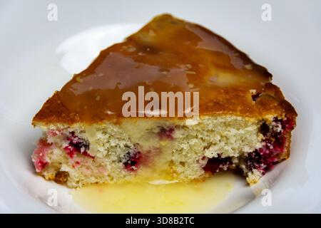 Extreme Nahaufnahme einer hausgemachten Cranberry-Tortenscheibe mit Zitronenglasur, die sich auf die feuchte, satte Krume und die glänzende Textur konzentriert. Appetitlich! Stockfoto
