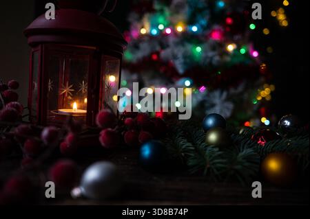 Rote Laterne mit Kerze und Weihnachtsdekoration vor einem beleuchteten Baum Stockfoto