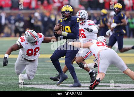 Ann Arbor, Usa. November 2025. Der Michigan Wolverines Quarterback Bryce Underwood (19) wird von Ohio State Buckeyes Kayden McDonald (98), Eddrick Houston (96) und Caden Curry (92) am Samstag, den 29. November 2025, entlassen. Foto: Aaron Josefczyk/UPI Credit: UPI/Alamy Live News Stockfoto
