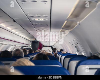 Innenansicht eines Geschäftsflugzeugs mit Sitzplätzen, geschlossenen Dachfächern und Gang in Richtung Cockpitbereich. Stockfoto