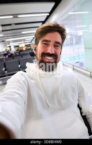 Ein lächelnder Mann macht Selfie am Flughafentor Stockfoto