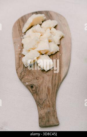 Leckerer frischer Käse, der auf einem rustikalen Holzbrett in kleine Stücke geschnitten ist, perfekt für eine Verkostung bei einer Versammlung. Stockfoto