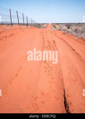 Ein hoher Zaun und eine rote Feldstraße; Dingo Fence, Australien Stockfoto