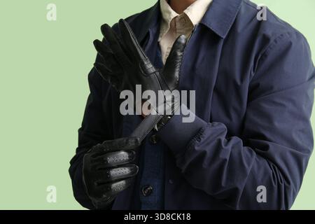 Mann trägt stilvolle Lederhandschuhe vor der farbigen Wand, Nahaufnahme Stockfoto