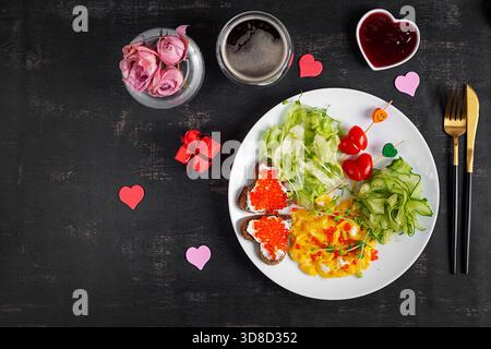 Romantisches Frühstück. Valentinstag. Omelette, Sandwiches mit rotem Kaviar und Salat. Stockfoto