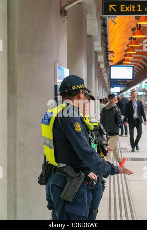 Melbourne, VIC, Australien. 30. November 2025. - Zwei uniformierte Sicherheitsoffiziere, einer mit einer gekapselten Waffe, stehen aufmerksam auf dem neuen Rathaus Stockfoto
