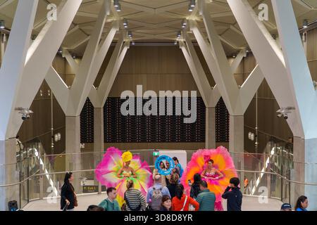 Melbourne, VIC, Australien. 30. November 2025. - Zwei Darsteller in großen, bunten Blumenkostümen interagieren mit eifrigen Besuchern im Rathaus Statio Stockfoto