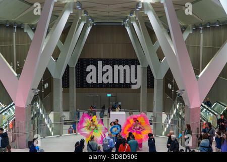 Melbourne, VIC, Australien. 30. November 2025. - Zwei Darsteller in großen, hellen Blumenkostümen feiern den Eröffnungstag des Rathausbahnhofs Stockfoto