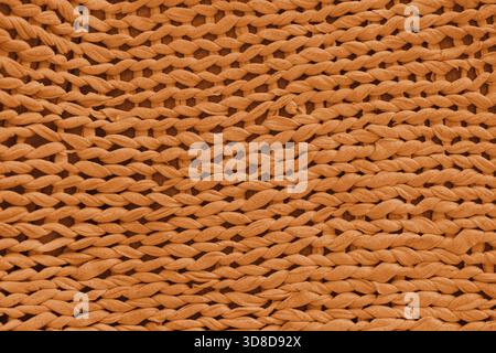 Makro, Nahaufnahme, detailliertes orangefarbenes Strickgewebe, Stoffstruktur mit grobem Garnmuster. Gemütlicher handgemachter Stoffhintergrund, Strickhintergrund, Stockfoto