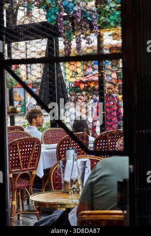 Paris, Frankreich - Juni 2025: Besucher genießen eine Mahlzeit in der Brasserie Le Dôme in Montparnasse. Das bunte Straßenleben spiegelt sich in einer lebendigen Kulisse wider. Stockfoto