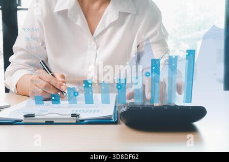 Geschäftsfrau analysiert Finanzberichte mit digitalen Balkendiagrammen und Datendiagrammen, die Finanzanalysen, Geschäftswachstum und Investitionspläne darstellen Stockfoto