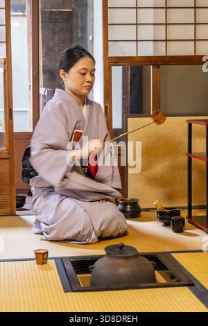 Kyoto, Japan: Japanische Frau im Kimono, die demonstriert, wie man Trraditional Matcha Tee während eines Teeaufrufs im Washitsu-Raum mit Tatami-Matten und Shoji-Schiebepapierschirmen zubereitet, Kyoto in Japan. Stockfoto