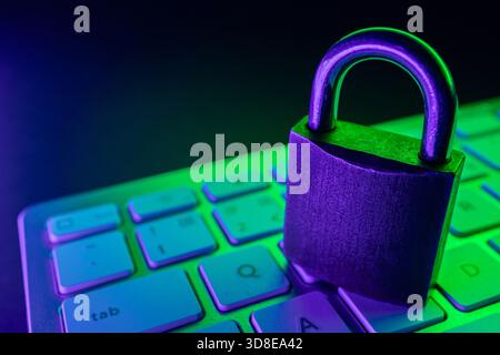 Ein Vorhängeschloss befindet sich auf einer Tastatur und symbolisiert die Cybersicherheit. Die farbenfrohe Beleuchtung unterstreicht die Bedeutung der Internetsicherheit beim Schutz von Daten und pe Stockfoto