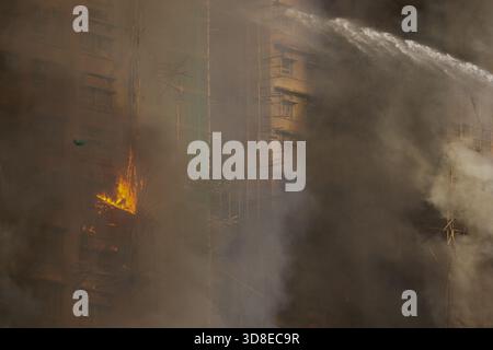 Feuerwehrleute, die Wasser als Großbrand sprühten, überfallen mehrere Wohngebäude am Wang Fuk Court am 26. November 2025 in Hongkong. Das Serval Wohngebäude im Wang Fuk Court im Tai Po District hat heute Feuer gefangen. Die Hong Kong Feuerwehr hat den Feueralarm Nr. 5 ausgegeben, der Brand zur lokalen Zeit sind 2300 13 Menschen tot und 30 verletzt nach Angaben der Regierung. (Foto von Ellan Mad/Nexpher Images) Stockfoto