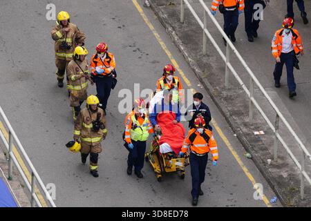 Rettungssanitäter ziehen einen Feuerwehrmann auf einer Bahre, während ein Großbrand mehrere Wohngebäude am Wang Fuk Court am 27. November 2025 in Hongkong erfasst. Das Serval Wohngebäude im Wang Fuk Court im Tai Po District hat heute Feuer gefangen. Die Hong Kong Feuerwehr hat den Feueralarm Nr. 5 ausgegeben, der Brand zur lokalen Zeit sind 2300 13 Menschen tot und 30 verletzt nach Angaben der Regierung. (Foto von Ellan Mad/Nexpher Images) Stockfoto