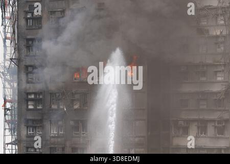 Feuerwehrleute, die Wasser als Großbrand sprühten, überfallen mehrere Wohngebäude am Wang Fuk Court am 26. November 2025 in Hongkong. Das Serval Wohngebäude im Wang Fuk Court im Tai Po District hat heute Feuer gefangen. Die Hong Kong Feuerwehr hat den Feueralarm Nr. 5 ausgegeben, der Brand zur lokalen Zeit sind 2300 13 Menschen tot und 30 verletzt nach Angaben der Regierung. (Foto von Ellan Mad/Nexpher Images) Stockfoto