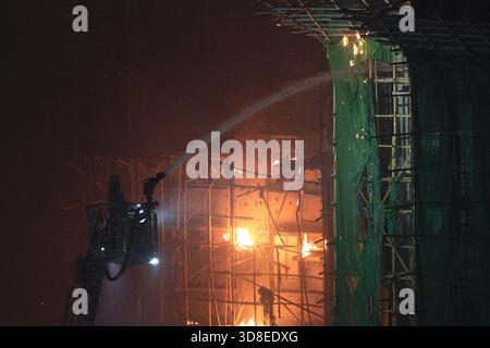 Hongkong, Hongkong . November 2025. Ein Feuerwehrmann auf einer Leiter sprüht Wasser, als ein Großbrand mehrere Wohngebäude am Wang Fuk Court am 26. November 2025 in Hongkong überfällt. Das Serval Wohngebäude im Wang Fuk Court im Tai Po District hat heute Feuer gefangen. Die Hong Kong Feuerwehr hat den Feueralarm Nr. 5 ausgegeben, der Brand zur lokalen Zeit sind 2300 13 Menschen tot und 30 verletzt nach Angaben der Regierung. (Foto von Ellan Mad/Nexpher Images/SIPA USA) Credit: SIPA USA/Alamy Live News Stockfoto