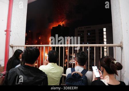 Hongkong, Hongkong . November 2025. Die Menschen beobachten, wie Rauch und Flammen aufsteigen, während ein Großbrand mehrere Wohngebäude am Wang Fuk Court am 26. November 2025 in Hongkong erfasst. Das Serval Wohngebäude im Wang Fuk Court im Tai Po District hat heute Feuer gefangen. Die Hong Kong Feuerwehr hat den Feueralarm Nr. 5 ausgegeben, der Brand zur lokalen Zeit sind 2300 13 Menschen tot und 30 verletzt nach Angaben der Regierung. (Foto von Ellan Mad/Nexpher Images/SIPA USA) Credit: SIPA USA/Alamy Live News Stockfoto