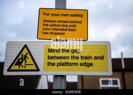 Zwei Warnschilder an Bahnsteigen warnen die Passagiere, hinter der gelben Linie zu bleiben und die Lücke zwischen Zug und Bahnsteig zu beachten. Stockfoto
